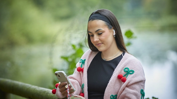 Young Woman Looking At Phone wearing earphones