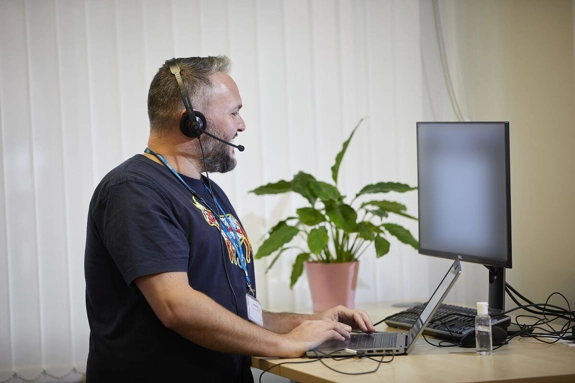 Male Staff With Headset At Computer Screen standing desk